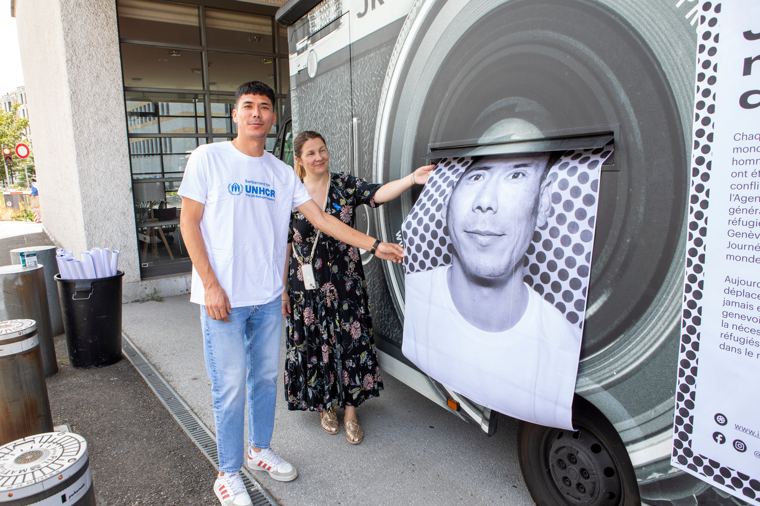A man holds a portrait photo of himself next to a mobile photography truck.